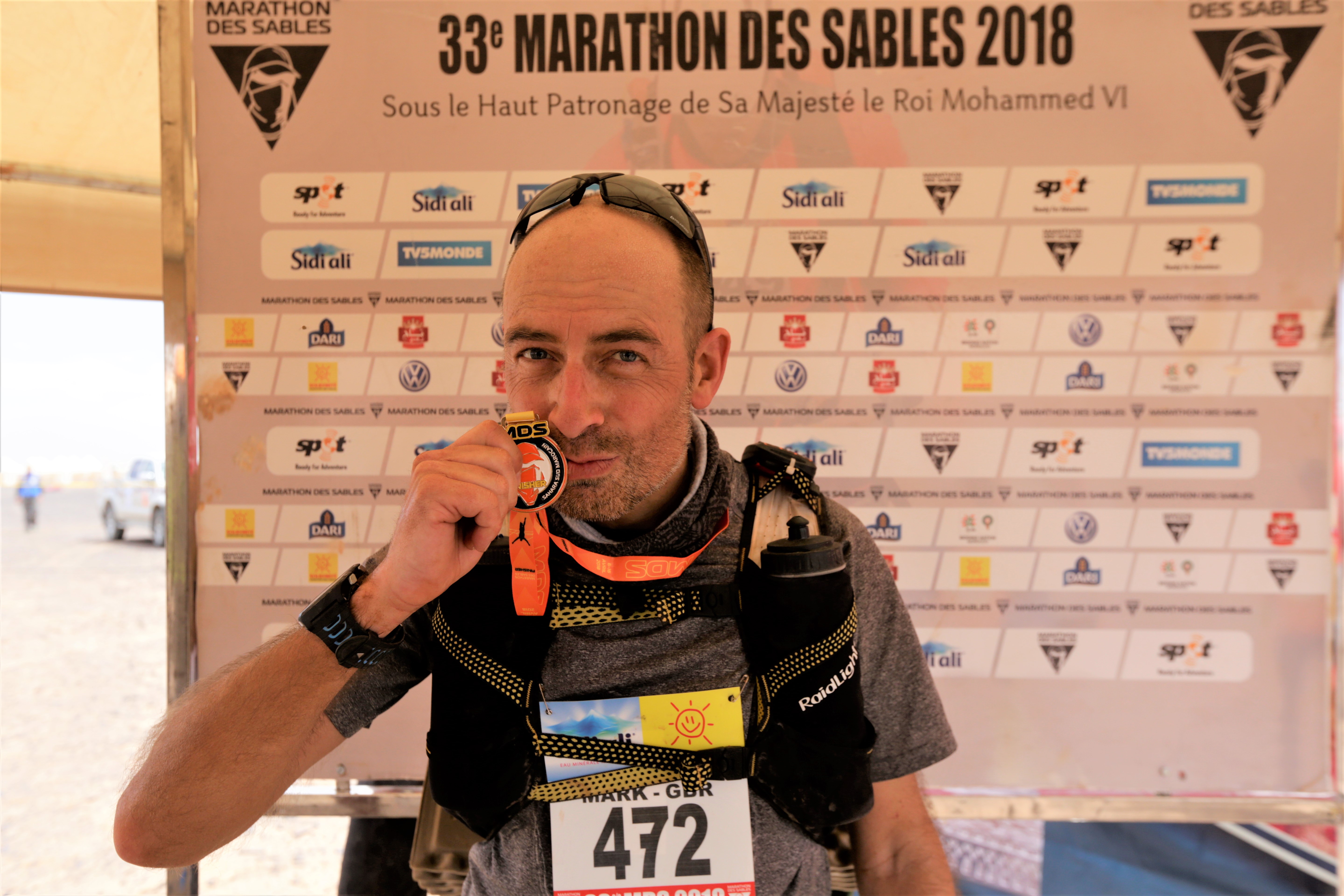 Mark Hillier holds his medal aloft after completing the Marathon des Sables