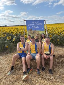 The Bournemouth AC group sitting on a bale of hay at the Sunflower Stride